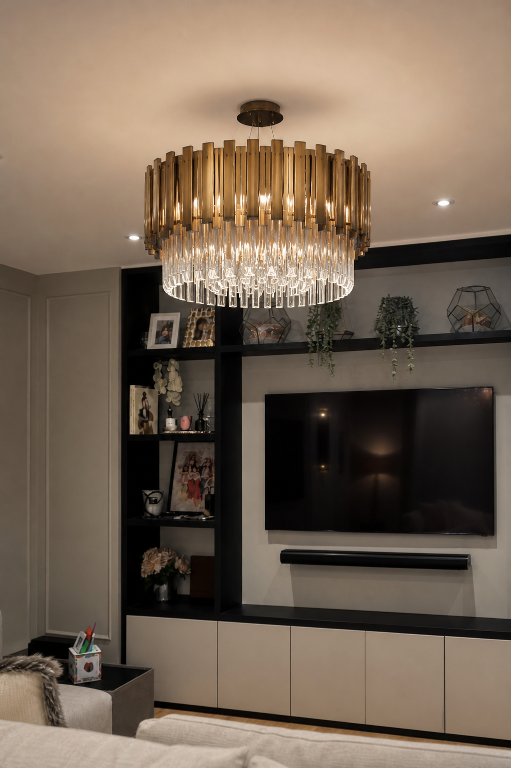 Close view of the tiered bronze and glass chandelier with the media wall behind