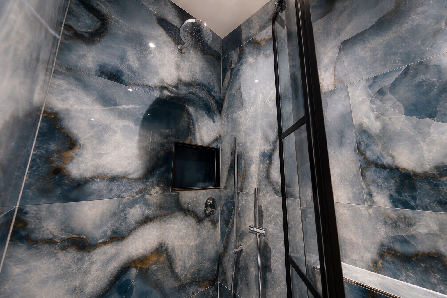 View from inside the shower showing the rain head, hand shower and recessed niche