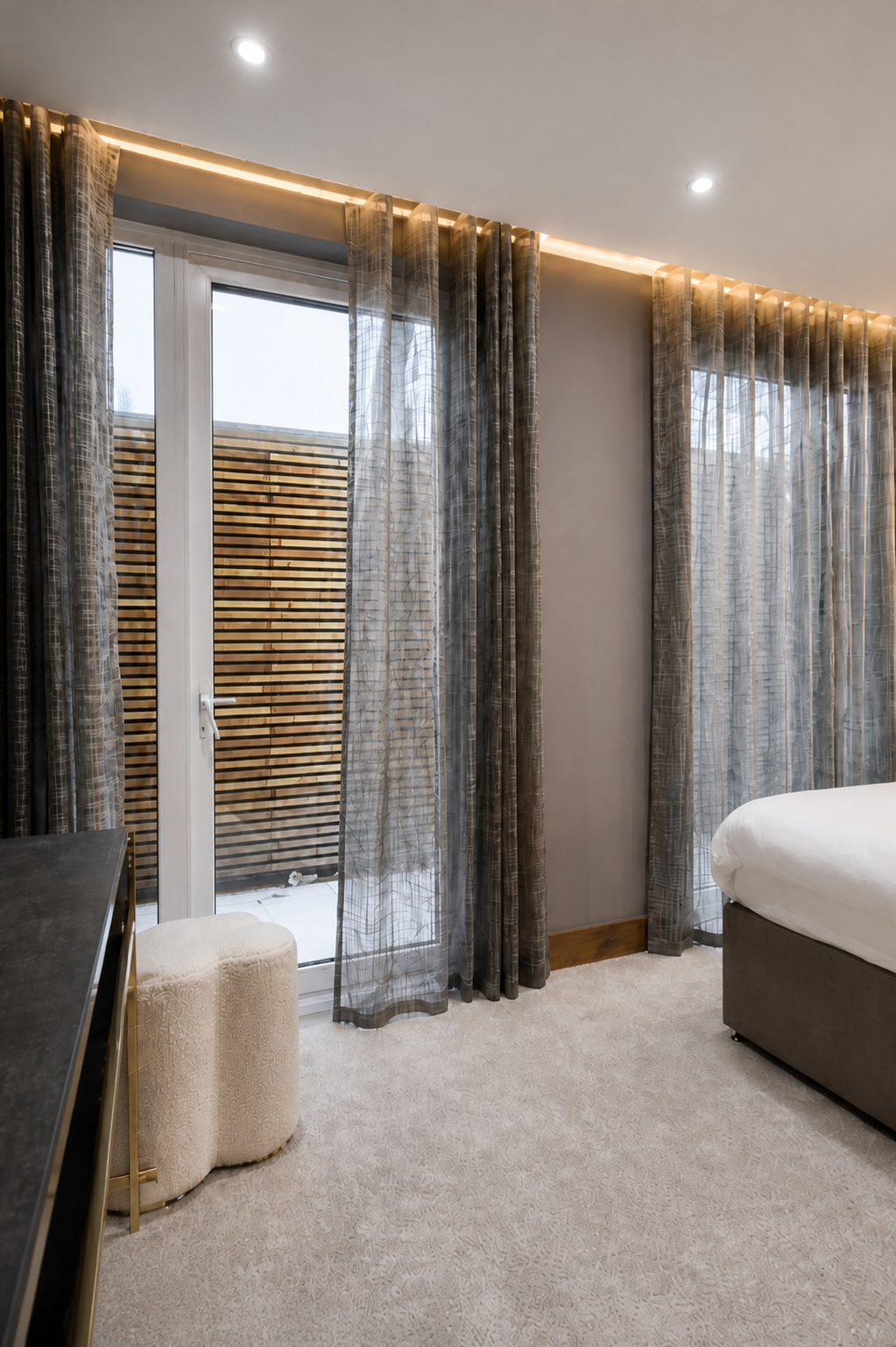 Close view of the bedroom French door, grey sheer curtains, timber privacy screen and concealed pelmet lighting